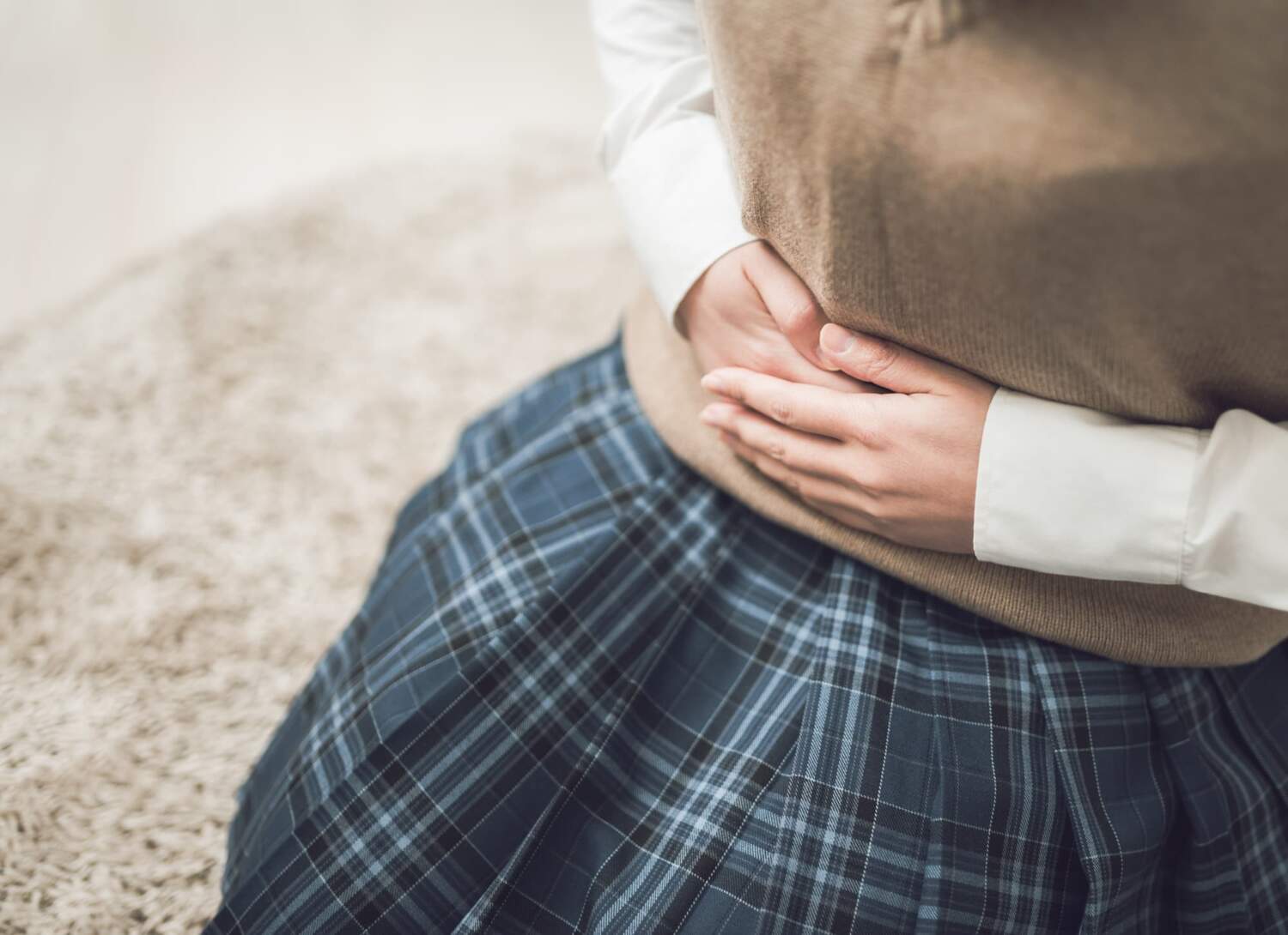 妊娠したお腹を押さえる制服姿の女の子