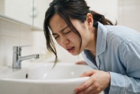 洗面所で吐きそうになっている女性